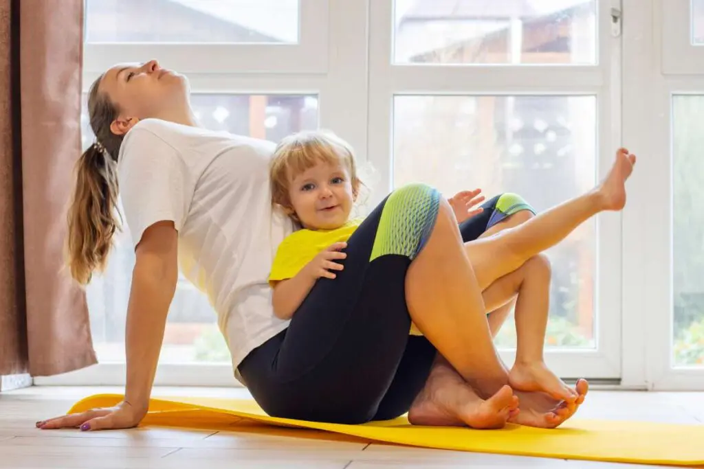 A woman holding a child while doing yoga.