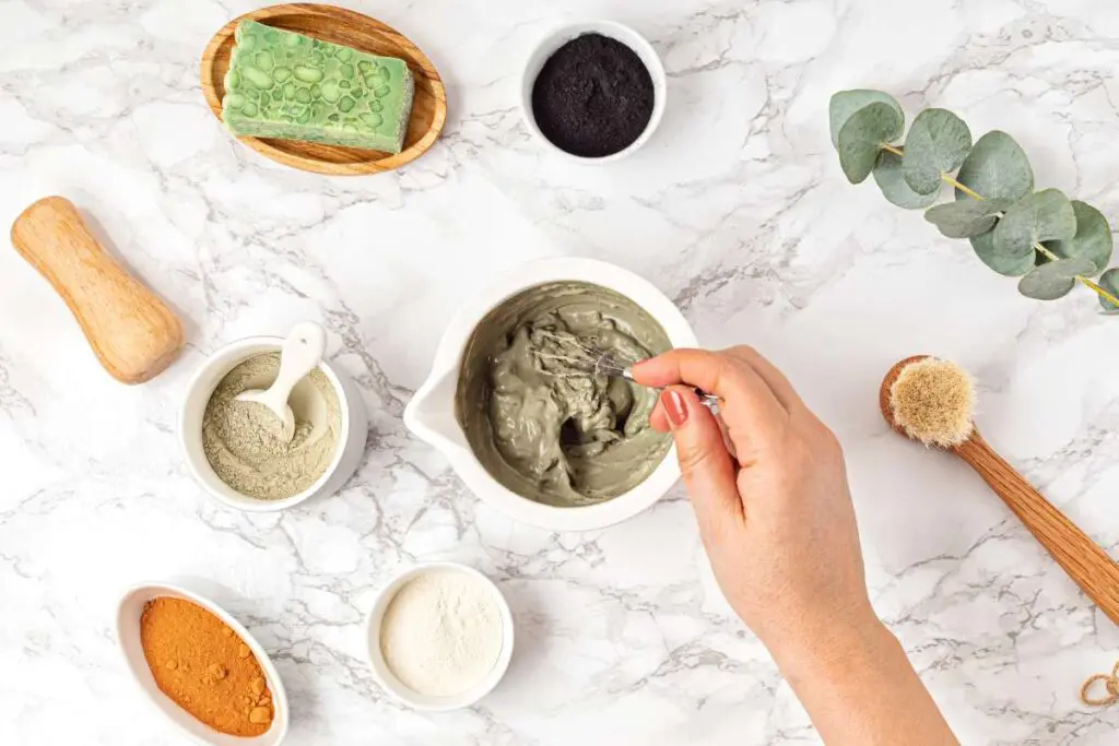 Top view of homemade clay facial mask beauty products, ingredients on light background.