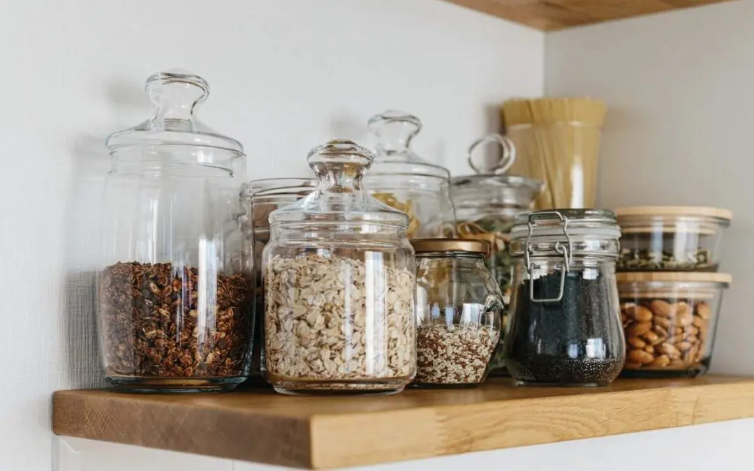 Glass jars filled with various dry foods on a shelf.