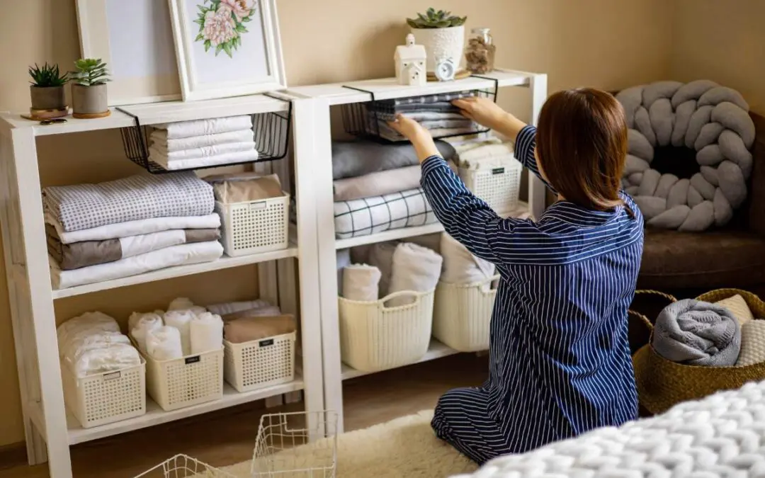 A woman is neatly putting folded linens into storage.