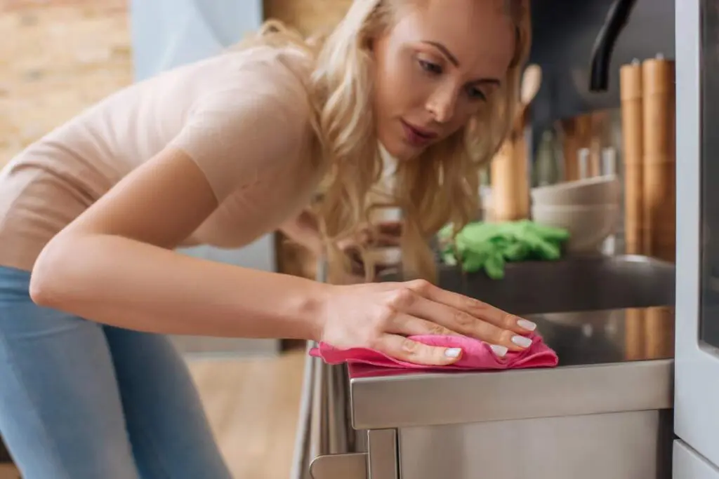 A woman wiping her stainless steel kitchen counter.
