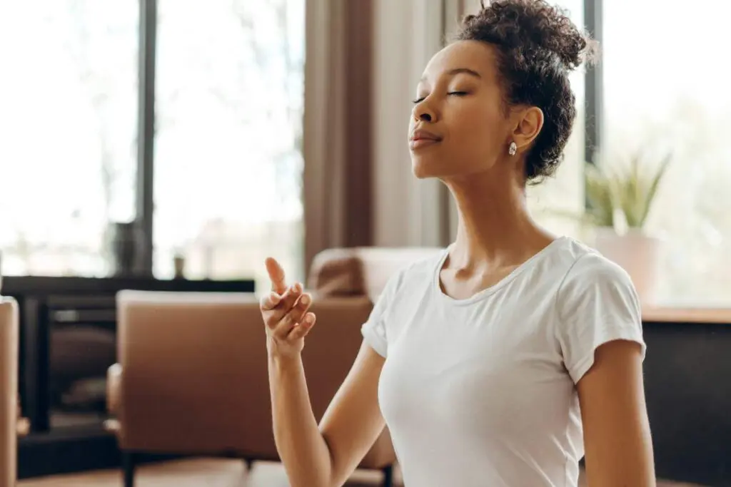 A woman is practicing deep breaths with her eyes closed.