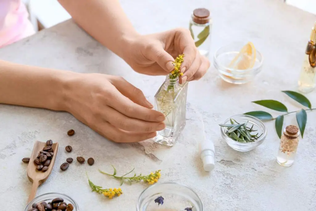 A woman making natural air fresheners with different ingredients laid out on the table.