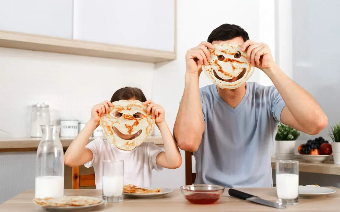 A man and a child hold pieces of bread in front of their faces.