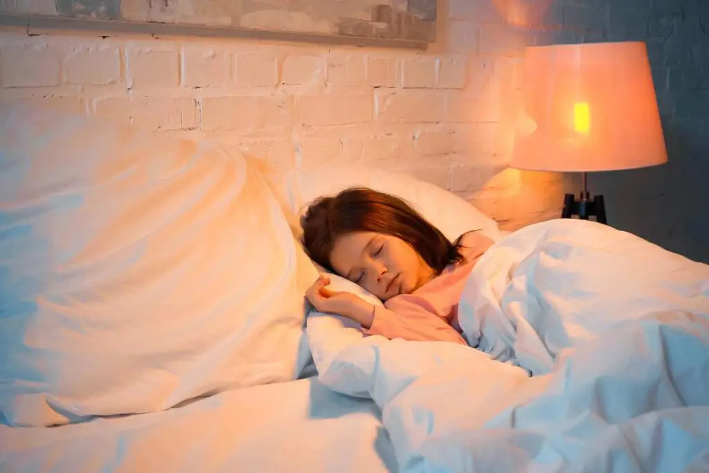 A girl is peacefully sleeping in a cozy bed, surrounded by soft bedding and a pillow.