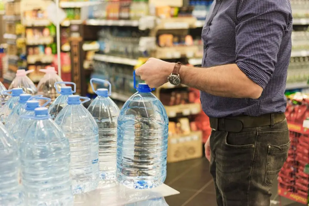 A man is holding a plastic water bottle inside a store.