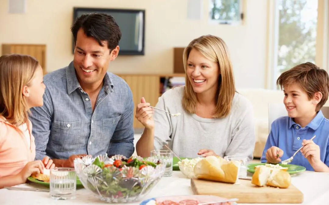 A family of four enjoying a meal together at a dining table, smiling and interacting.