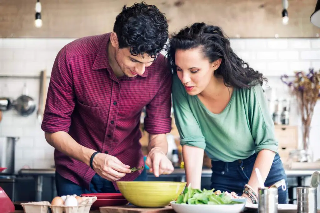A man and a woman are preparing food together in a bright kitchen.