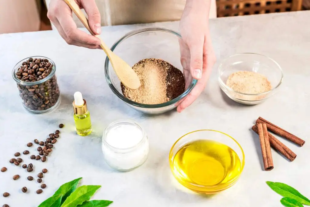 A person mixing ingredients in a glass bowl with a wooden spoon, surrounded by various containers.
