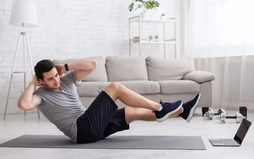 A man performing a bicycle crunch exercise on a yoga mat in a modern living room, with a laptop showing workout instructions nearby.