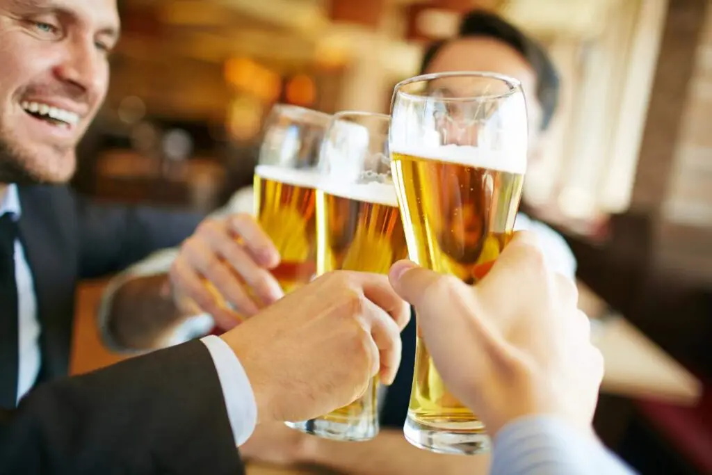 A group of people toasting with glasses of beer in a casual setting.