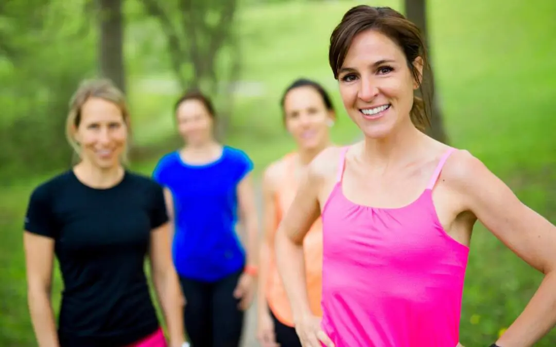 A group of four women in athletic wear smiling and posing outdoors.