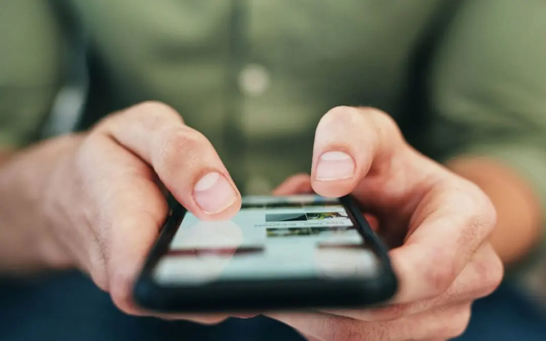 A person holding a smartphone and interacting with the screen using their fingers.