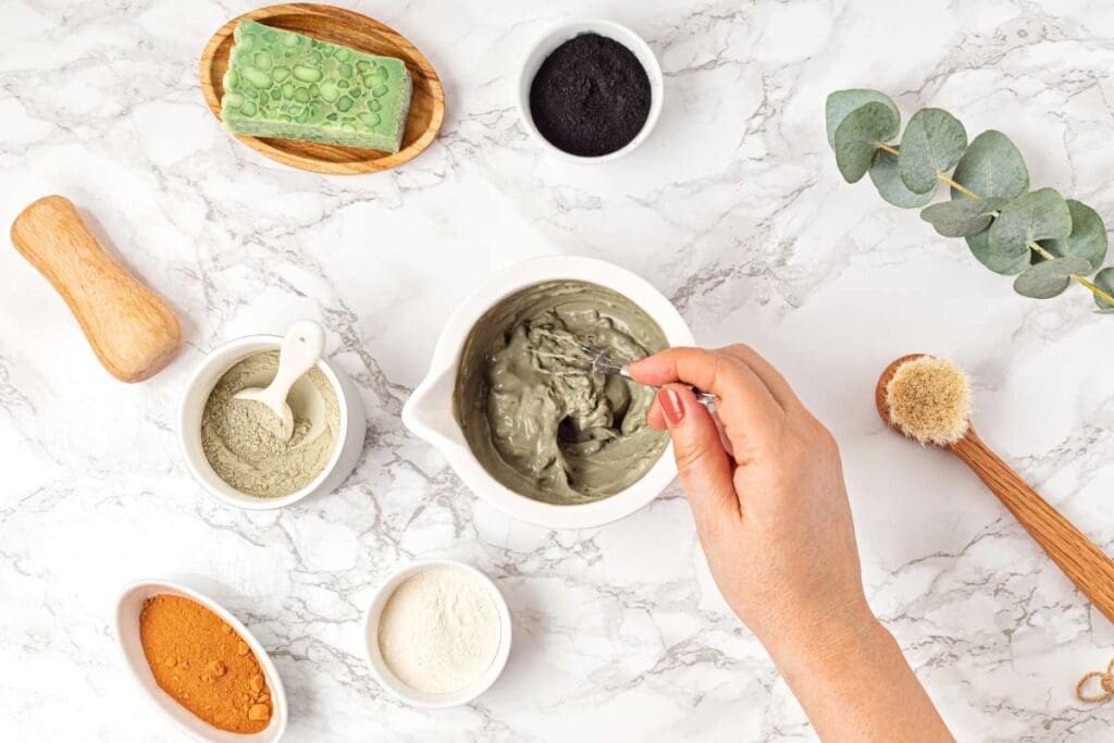 Top view of homemade clay facial mask beauty products, ingredients on light background.