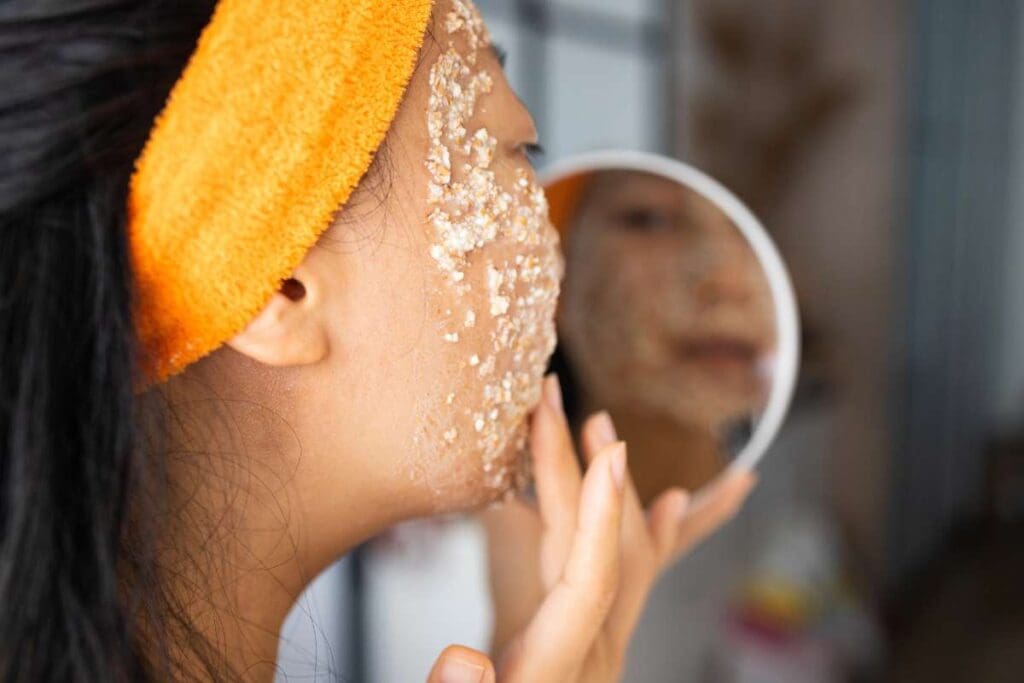 Woman applying facial oatmeal while looking in the mirror.