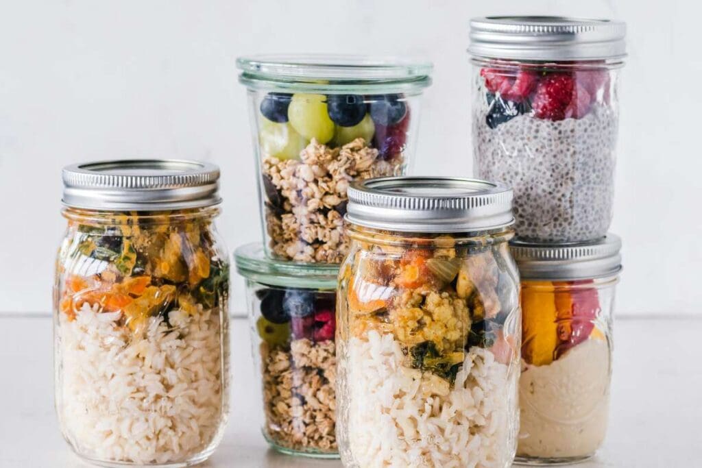 Six glass jars filled with layered food ingredients contains different colorful mixtures.