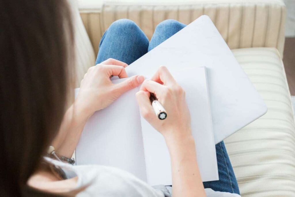 Woman writing while sitting on a couch.