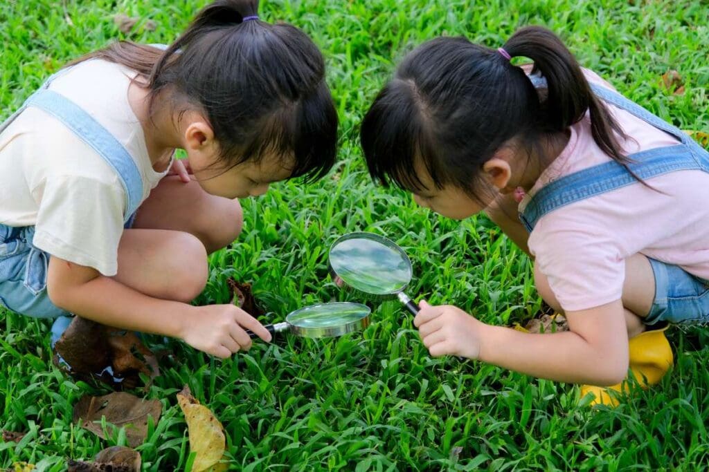 Children learn and explore nature with an outdoor magnifying glass.