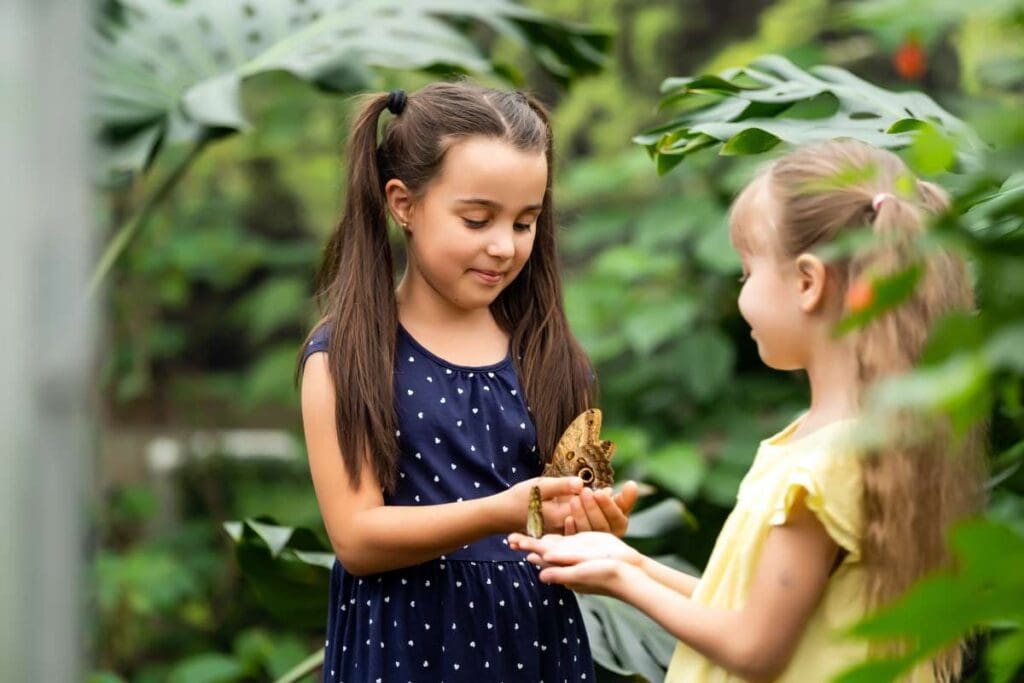 Two children holding a butterfly in their hands.