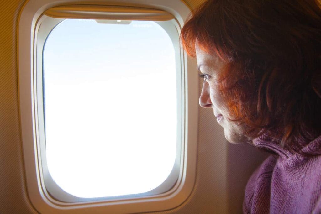 A woman looking out the airplane window.